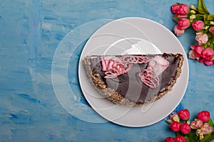 Half of cake on white plate on blue painted background. Sweet bakery with flowers, top view, copy space