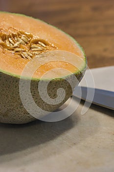 cantaloupe and knife on white cutting board on table