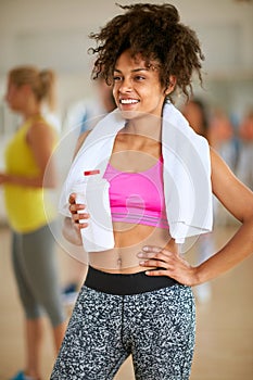 Half-caste woman with towel and bottle of protein shake after tr