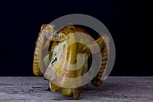 Half of chicken, baked in oven with black olives in oil, Christmas decoration, wooden background, side view.