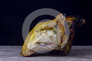 Half of chicken, baked in oven with black olives in oil, Christmas decoration, wooden background, side view.