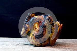 Half of chicken, baked in oven with black olives in oil, Christmas decoration, wooden background, side view.