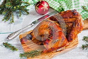 Half of chicken, baked in oven with black olives in oil, Christmas decoration, wooden background, top view