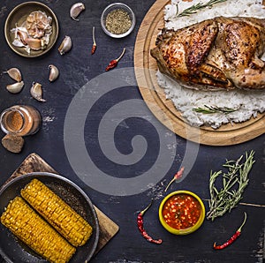 Half chicken with rice on a cutting board with spices, corn and herbs, place for text,frame wooden rustic background top view