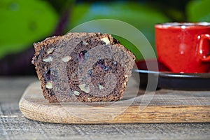 Half chocolate muffin with blueberries and walnuts on a wooden table, closeup. Sweet pastries on the board. Fresh cupcakes for