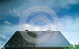 A half cleaned house roof shows the before and after effect of a roof cleaning