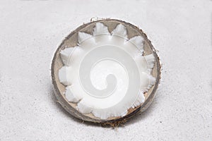 Half coconut lying in white sand