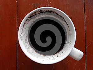 half of a cup coffee was left with dregs one rainy afternoon shot closely in wood background