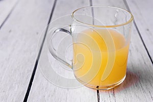Half cup of orange juice on a white wooden background