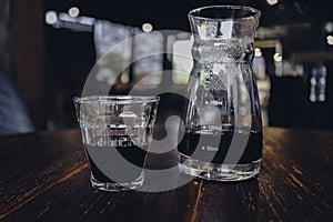 Half cup of v60 black coffee and unique beaker coffee glass jar on the wooden table