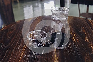 Half cup of v60 black coffee and unique beaker coffee glass jar on the wooden table