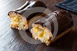 Half Cut Cream Filled Chocolate Eclairs on Dark Wooden Surface.