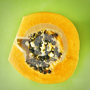 Half cut papaya fruits on green background. Square photo image.