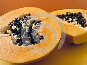 Half cut papaya on orange background.