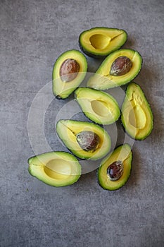 Half cut ripe avocados with seed on dark grey background, top view flt lay