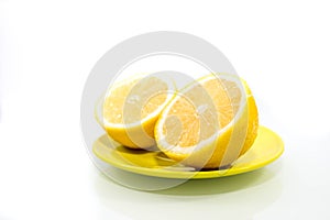 Half cutted lemons on vibrant green plate isolated on white