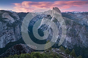 Half Dome and Yosemite Valley in Yosemite National Park during colorful sunset with trees and rocks. California, USA