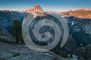 Half Dome and Yosemite Valley in Yosemite National Park during colorful sunset with trees and rocks. California, USA