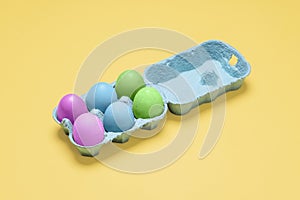 Half dozen dyed easter eggs in egg carton container