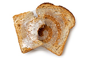 Half eaten buttered slice of whole wheat toast and whole dry slice of toast isolated on white from above.