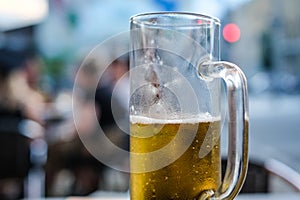 Half empty glass of light beer in a pub. Selective focus