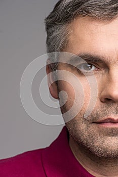 Half face of adult man on grey background.