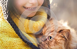 Half face of little girl in yellow pullover with red persian cat