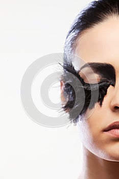 Half face of a model with black false feather eyelashes bold black eye makeup