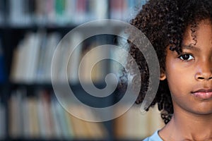 Half face portrait of african american schoolboy with afro hair in library with copy space photo