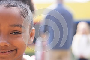 Half face portrait of smiling african american elementary schoolgirl in schoolyard, copy space photo