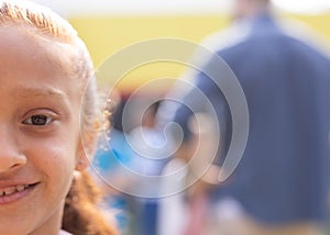 Half face portrait of smiling biracial elementary schoolgirl in school playground, copy space photo