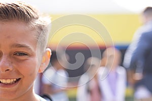 Half face portrait of smiling caucasian elementary schoolboy in school playground, copy space photo