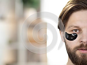 Half of face of young handsome bearded Caucasian man with black eyes patches