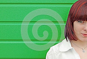 Half of the face of a young red-haired woman in front of a green gate