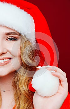 half faces. a beautiful woman in a Santa Claus hat on a red background.