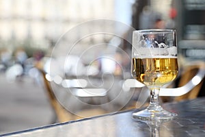 Half-finished glass of beer stands on gray windowsill.