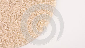 Half frame circle shaped heap of raw white rice rotating on turn table. Isolated on white. Loopable. Close up macro. View from abo