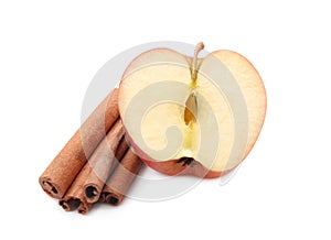 Half of fresh apple and cinnamon sticks on white background