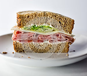 Half of a fresh deli ham and cheese sandwich on wheat bread. Isolated on white background.