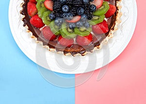 Half a fresh summer fruit pie on plate pink blue backgrounds