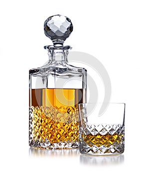 A half full crystal whisky decanter, and crystal glass, with golden whisky, shot on white