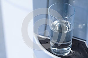 Half full glass in water dispenser