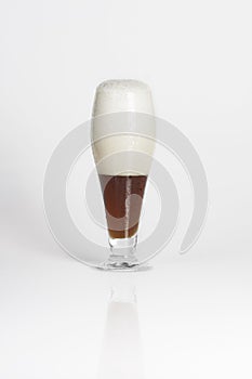 Half of glass of cold dark beer