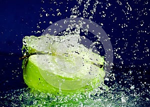 Half of green apple with stopped motion water