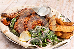 Half grilled chicken with salad, wedges, lemon and dip served in dish isolated on background top view of arabic food