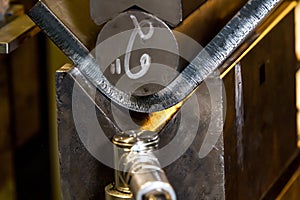 Half inch steel being bent in press with vibration sensor showing scale on steel edge - macro