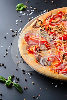 Half of italian pizza and fresh basil leaves on a dark backgroud, close up. Traditional italian cuisine