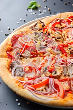 Half of italian pizza and fresh basil leaves on a dark backgroud, close up. Traditional italian cuisine