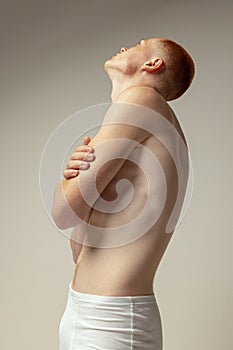 Half-legth portrait of handsome young man posing in white underwear isolated over grey studio background. Men& x27;s