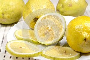Half lemon and slices beside several full lemons